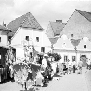 Vintage outdoor market with clothing stalls.
