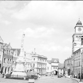Historic European town square with clock tower and fountain.