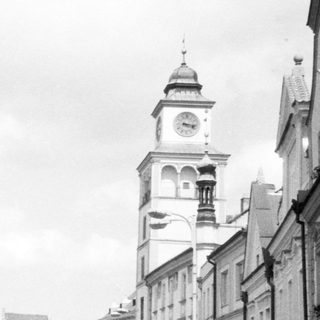 Historic European town square with clock tower and fountain.