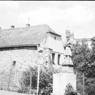 Statue near historic stone building with church spire.
