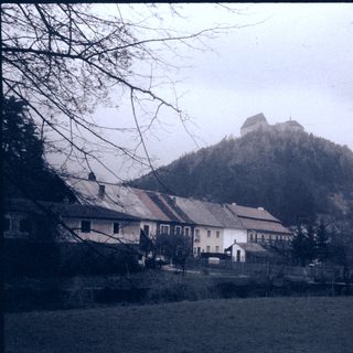 Rural village with castle ruins on hill.