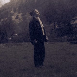 Man standing in field with castle on hill.