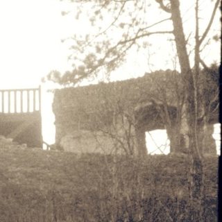 Abandoned stone watchtower in overgrown forest terrain.