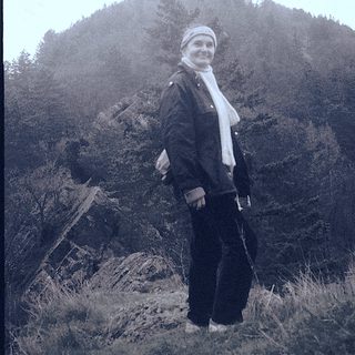 Woman standing on hillside near castle ruins.