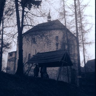 Historic stone tower with scaffolding, surrounded by trees.