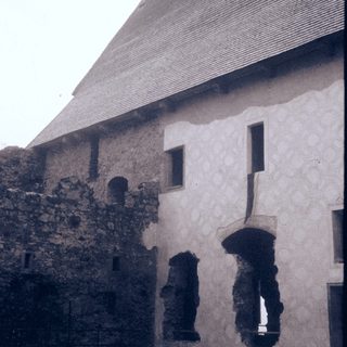 Historic stone and plaster building with arched window openings.