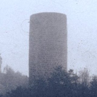 Castle ruins atop hill with tall tower.
