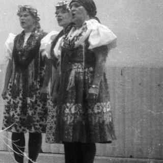 Traditional folk group performing with floral wreaths.