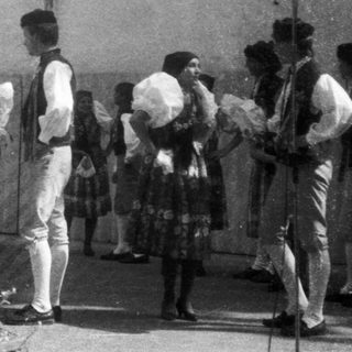 Group performing traditional folk dance outdoors.