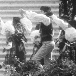 Traditional folk dance performance with women in skirts and headscarves.