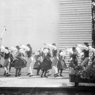 Traditional folk dance performance with women in skirts and headscarves.