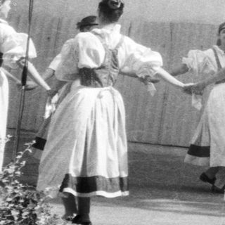 Group performing traditional folk dance with hand-holding.