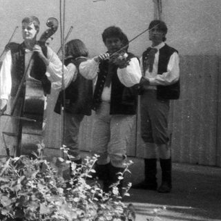 Traditional folk band performing outdoors in folk costumes.