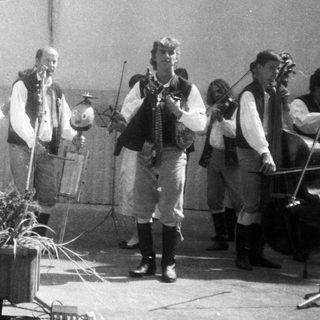 Traditional folk band performing with singer in regional attire.