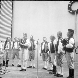 Group of men in traditional attire performing outdoors.