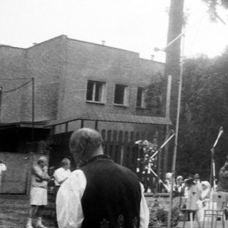 Ceremonial outdoor event with flags and wreaths.