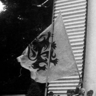 Ceremonial flag-raising and wreath-laying event outdoors.