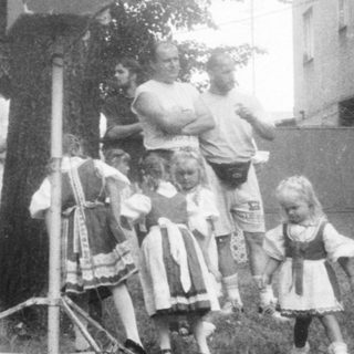 Group of people and children gathered around an old-fashioned telephone booth.