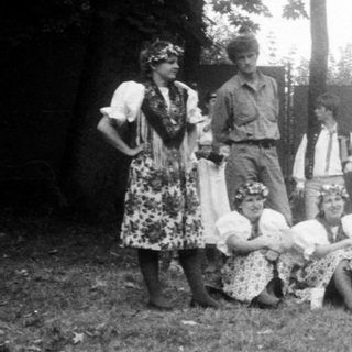 Group of people and children gathered around an old-fashioned telephone booth.