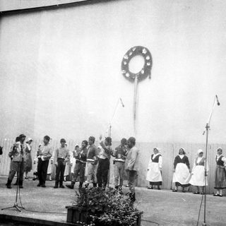 Group performing traditional folk song outdoors.