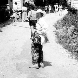 Rural village street with people walking, traditional wooden houses.