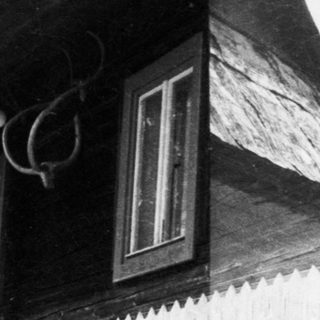 Traditional wooden house with steep roof and stairs.