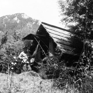 People in rural outdoor setting near simple shelter.