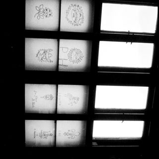 Stained glass window panels with heraldic and floral designs.