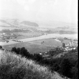 Rural landscape with winding river and misty hills.