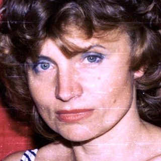 Woman in striped swimsuit against red backdrop.