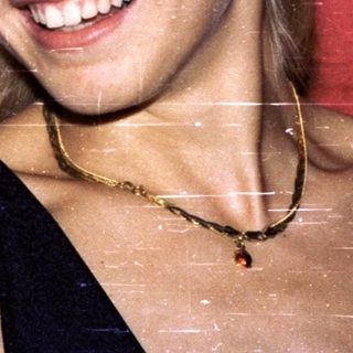 Woman wearing blue cap, smiling against red backdrop.