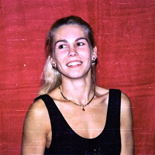 Blonde woman smiling in black top.
