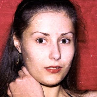 Young woman posing against red backdrop.
