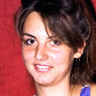 Woman smiling in blue swimsuit against red background.