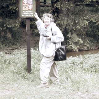 Person posing near hiking trail sign.