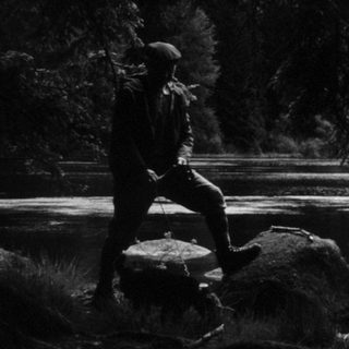 A person sitting on rocks by a serene lake.
