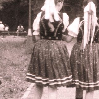 Traditional folk dancers in rural outdoor setting.