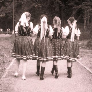 Traditional folk dancers in rural outdoor setting.