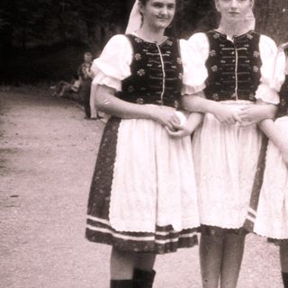 Four women in traditional folk dresses posing outdoors.
