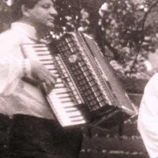 Traditional folk group performing outdoors with accordion and costumes.