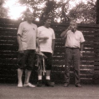 Group of people posing outdoors near wooden fence.