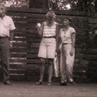 Group of people posing outdoors near wooden fence.