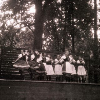 Traditional folk dancers performing outdoors in vintage attire.