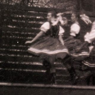 Traditional folk dancers performing outdoors in vintage attire.