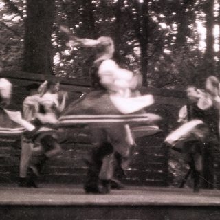 Blurred dancers performing acrobatic moves on rotating chairs.