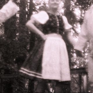 Traditional folk dancers in rural attire performing outdoors.