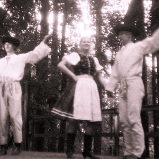 Traditional folk dancers in rural attire performing outdoors.