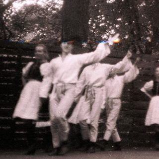 Group performing traditional dance outdoors in forest.