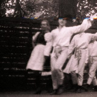 Group performing traditional dance outdoors in forest.