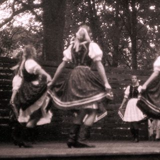 Traditional folk dancers in forest setting.